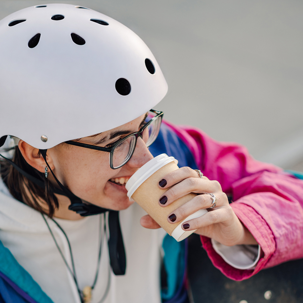 Smiling skater drinking coffee after exercising outdoors